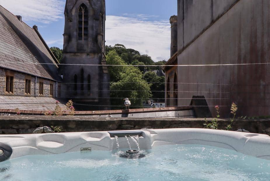 Cottage patio with hot tub and view of stone church building