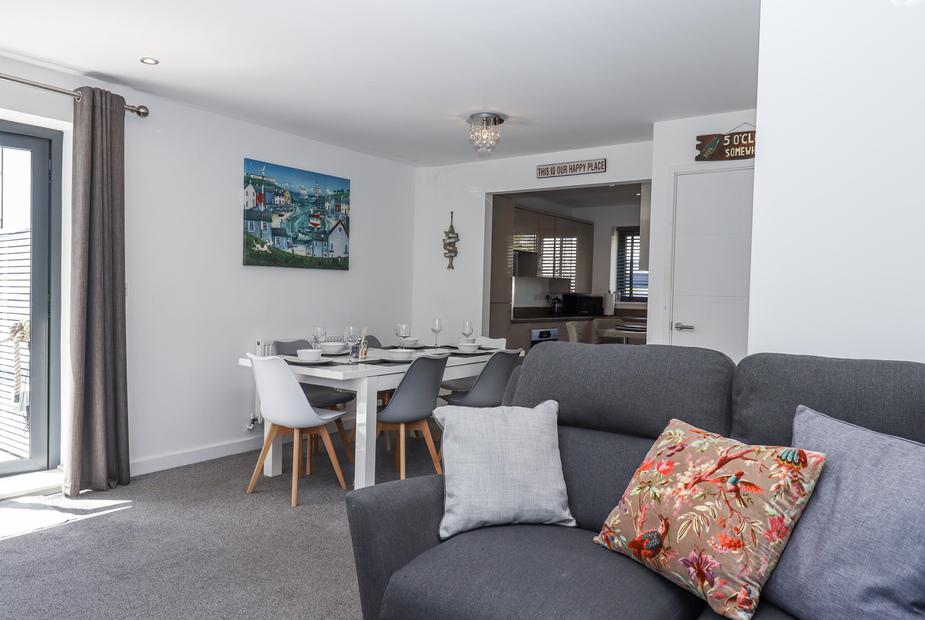 Cottage dining area with set table and grey sofa in the foreground