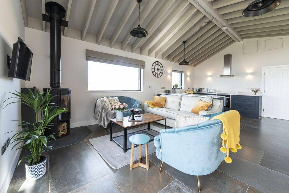 Lodge open-plan living area with wood-burning stove, sofa, and kitchen in background