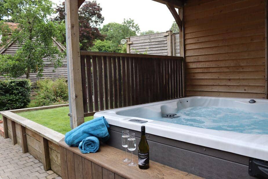 Cottage patio with hot tub, towels, wine bottle and glasses on wooden decking