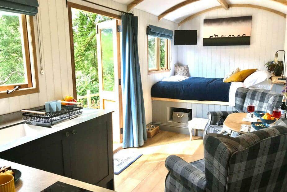 Lodge interior with kitchenette, bed and small dining table by open door