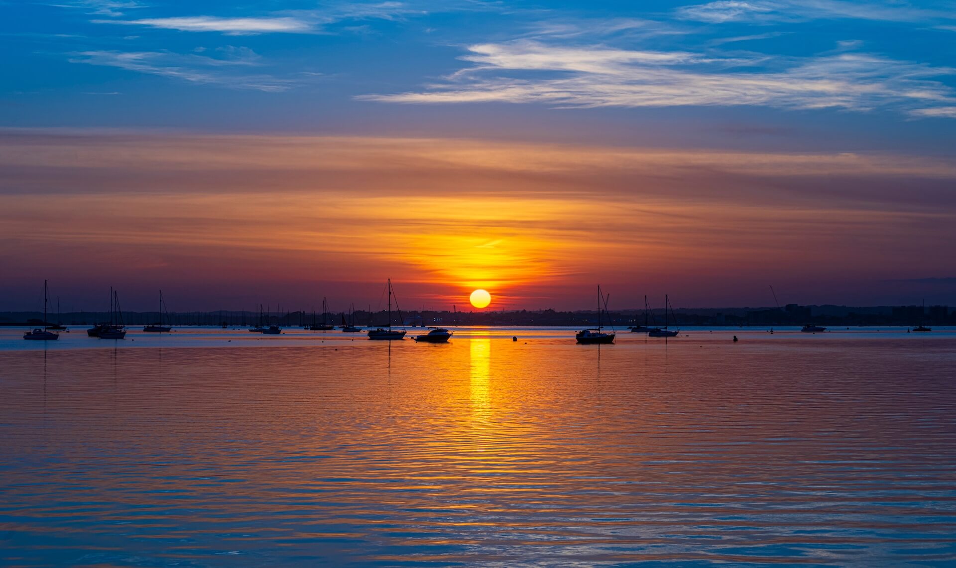 Luxury boats moored at Sandbanks during a golden sunset near Bournemouth.