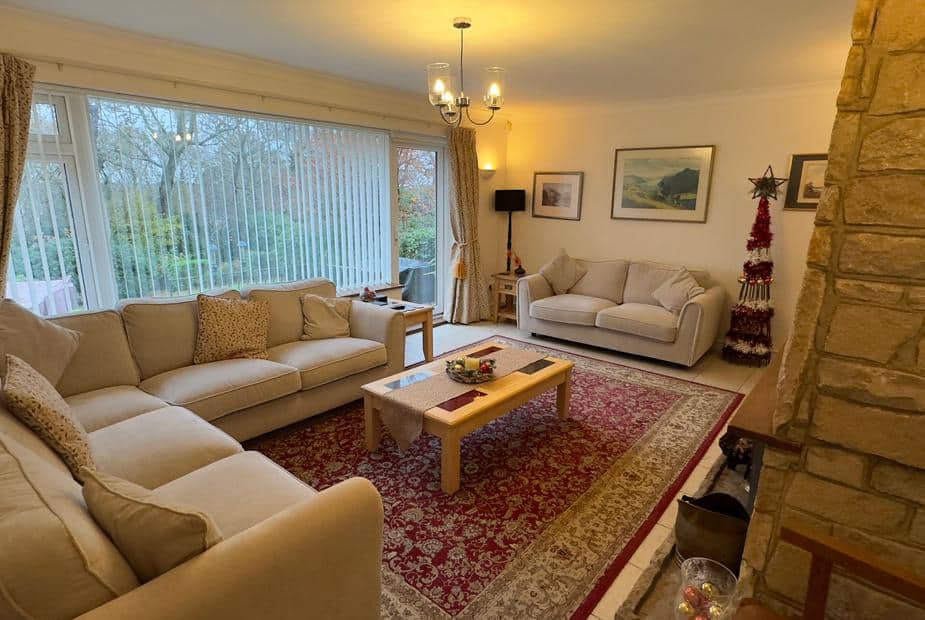 Cottage living room with cream sofas, coffee table and large window overlooking garden