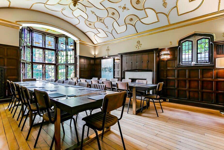 Cottage dining room with long table, chairs and stained glass bay window