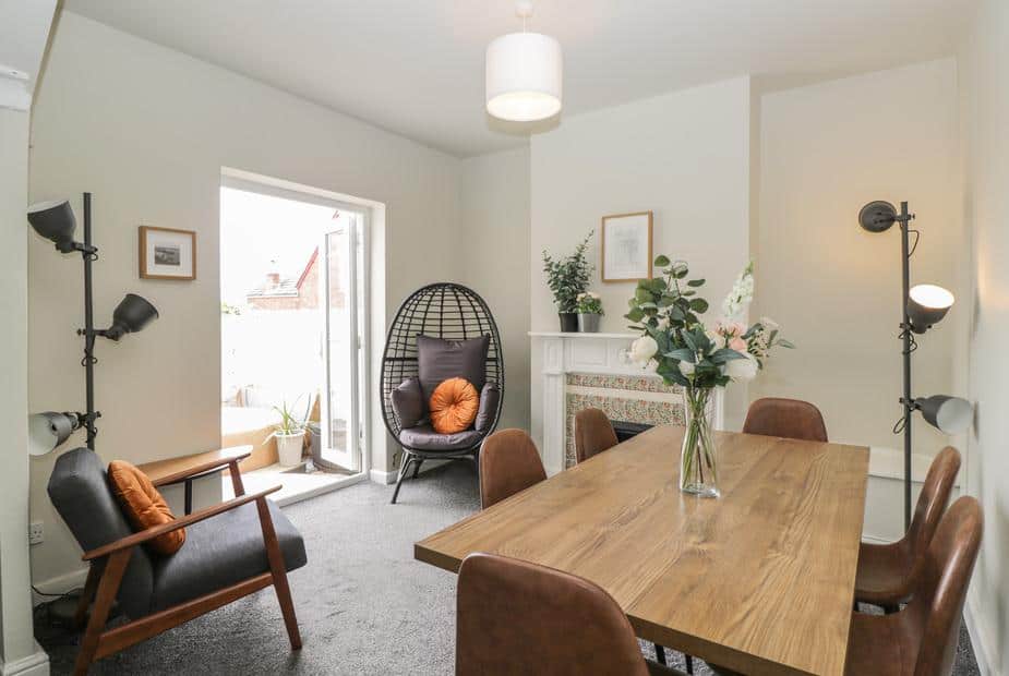 Cottage dining room with wooden table, armchairs and egg chair by patio doors