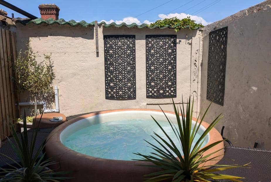 Cottage courtyard with circular hot tub and decorative wall panels