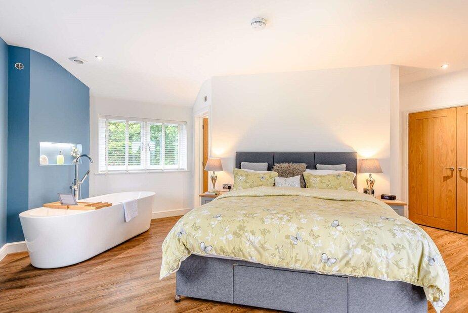 Cottage bedroom with double bed and freestanding bathtub by window