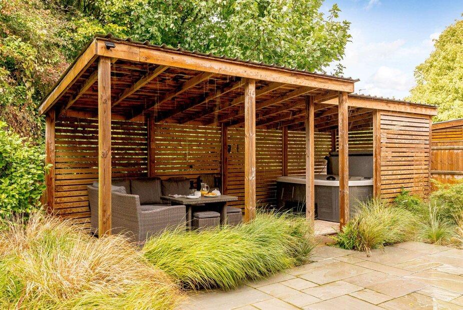 Covered patio seating area with hot tub in cottage garden