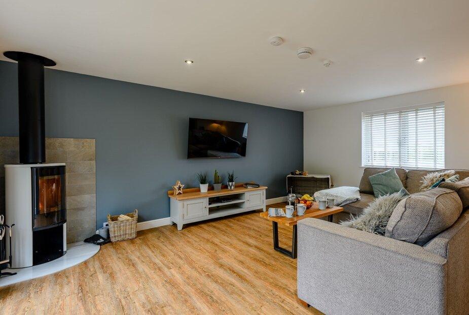 Cottage living room with wood burner, TV and grey corner sofa