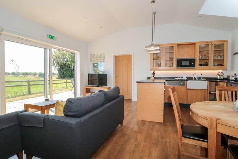 Lodge open-plan living area with sofa, kitchen, dining table and patio doors to outside