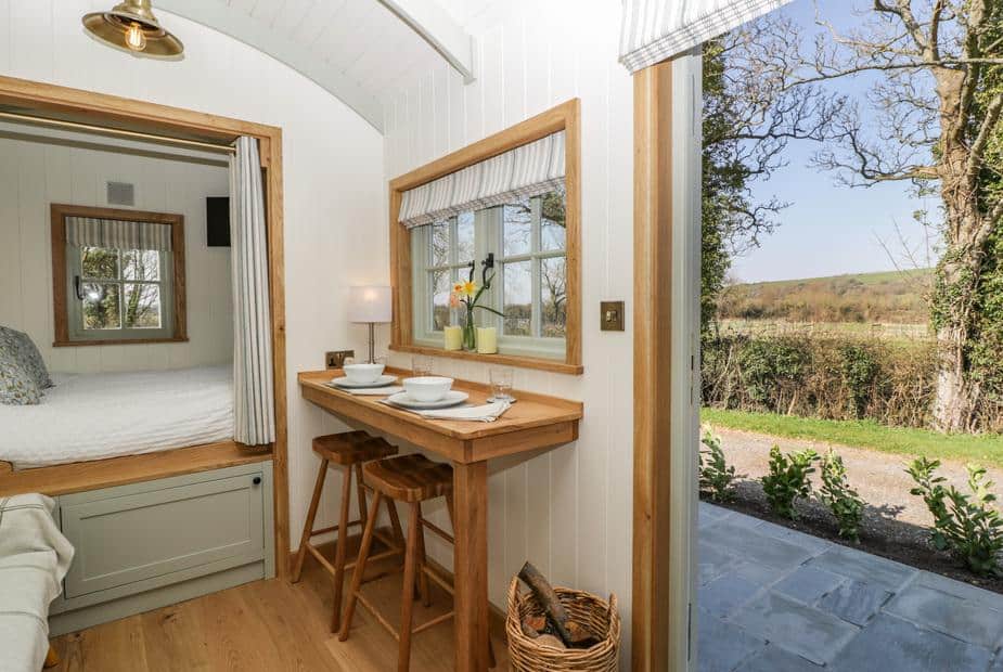 Cottage kitchen with breakfast bar, stools and open door to garden view