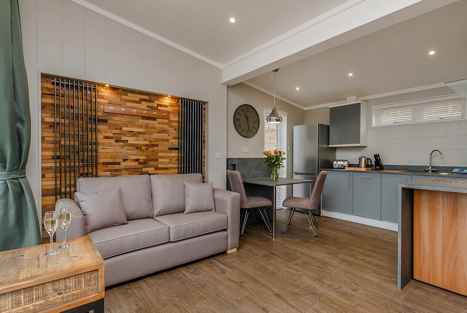 Lodge living area with sofa, wood panel feature wall and open-plan kitchen