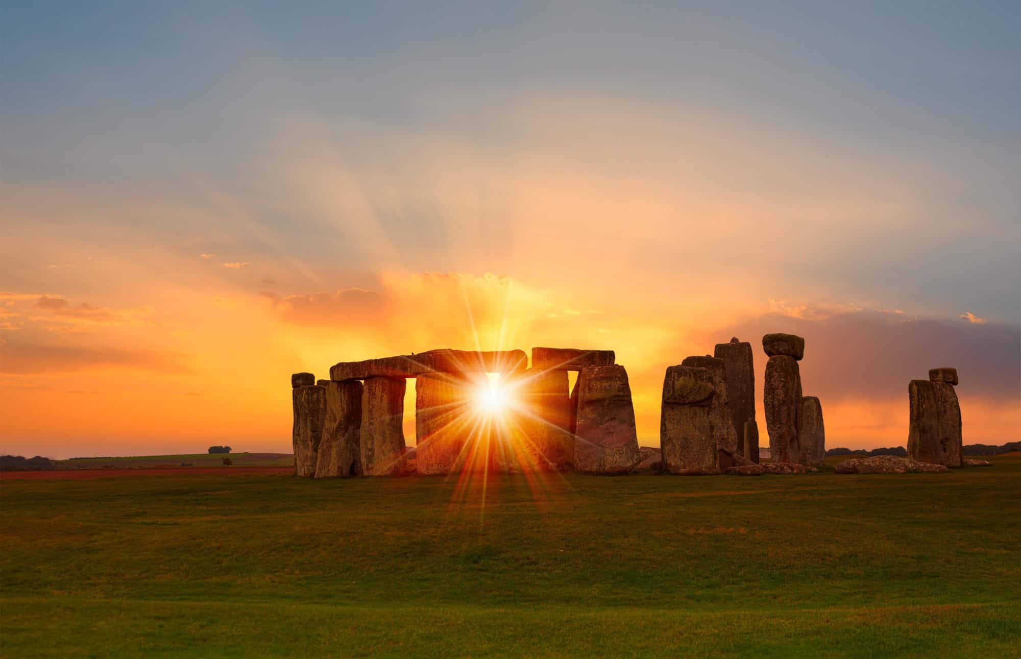 Sunburst shining through the ancient standing stones of Stonehenge in Wiltshire.