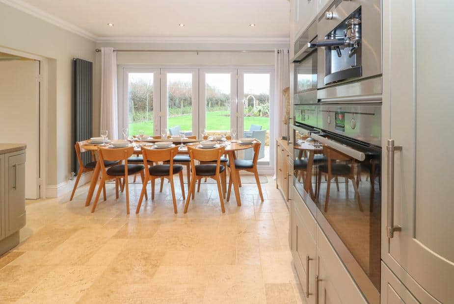 Cottage kitchen with dining table set for eight and view to garden through patio doors