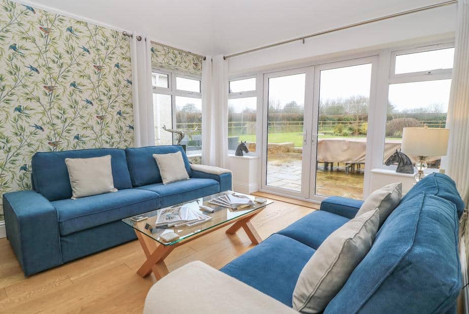 Cottage lounge with blue sofas and glass coffee table by patio doors