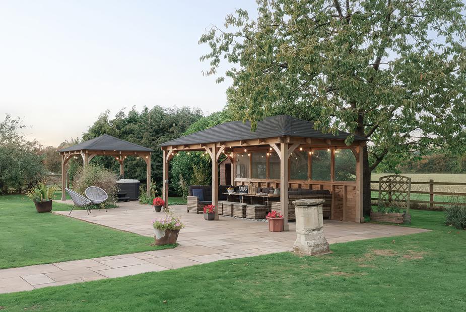 Covered patio seating area in garden with outdoor furniture and potted plants