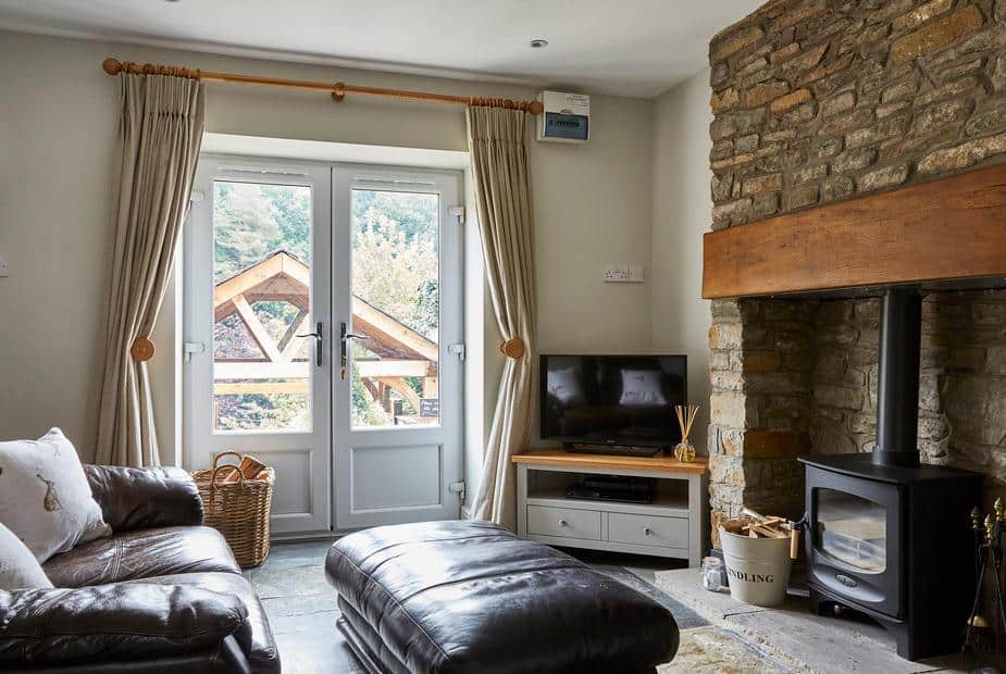 Cottage lounge with wood burner, stone fireplace, and double doors to garden.