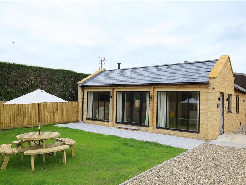 Park Bothy with large glass doors and a picnic table with umbrella in fenced garden