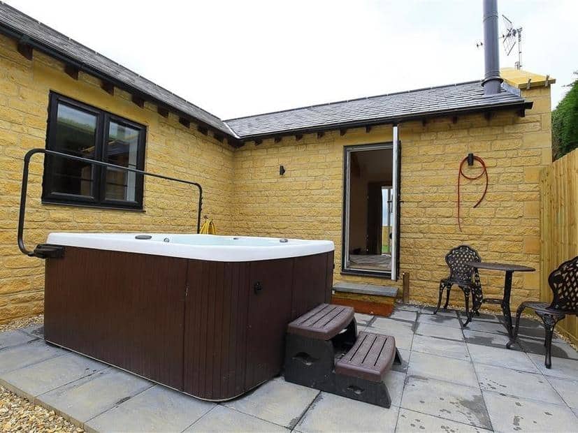 Cottage patio with hot tub and small metal table and chairs