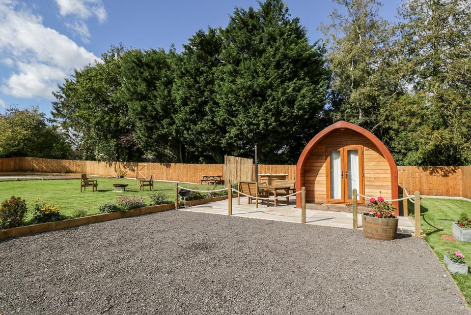 Halmore Pod with outdoor seating area and surrounding garden under large trees