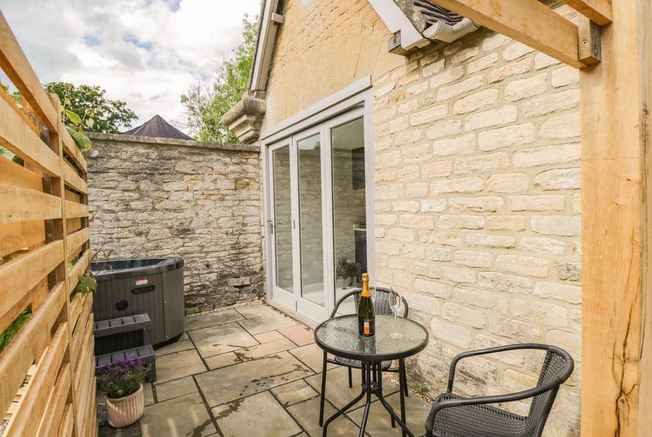 Cottage patio with bistro table, chairs and hot tub by stone wall