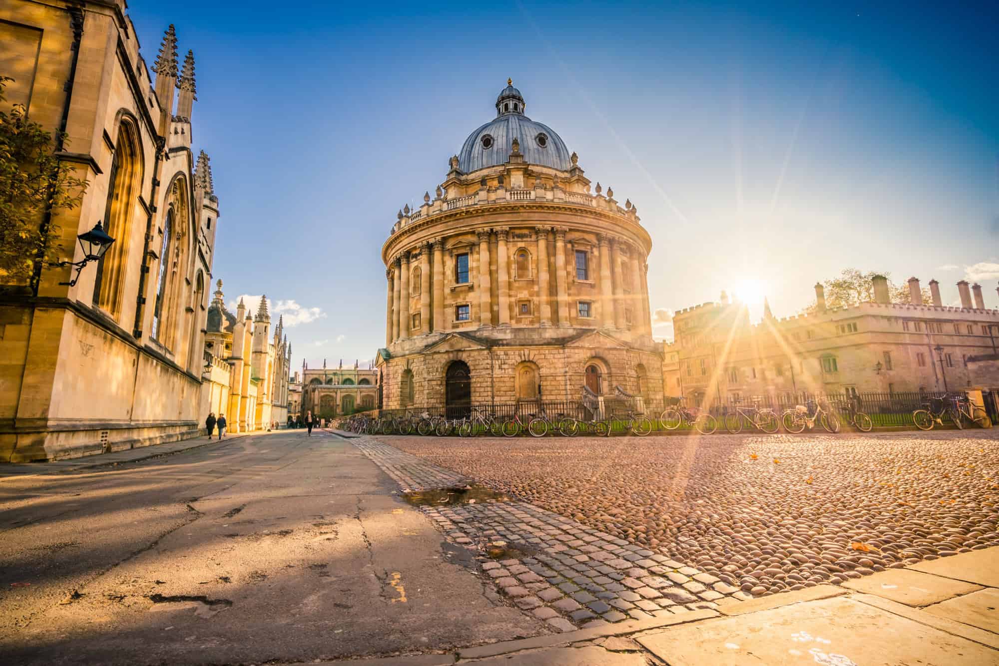 Sunburst shining over the historic Radcliffe Camera and cobblestone streets in Oxford.