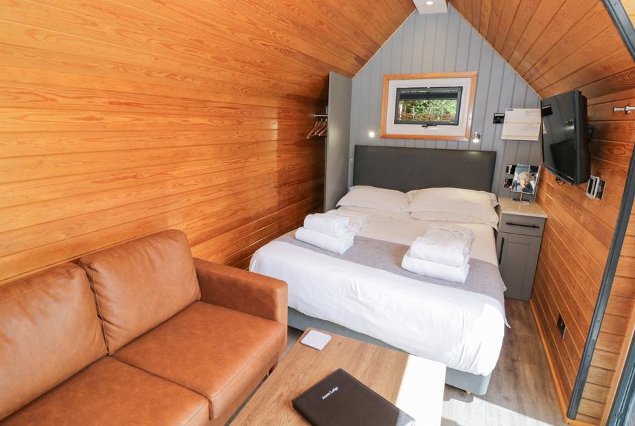 Lodge interior with double bed, sofa, and wall-mounted television