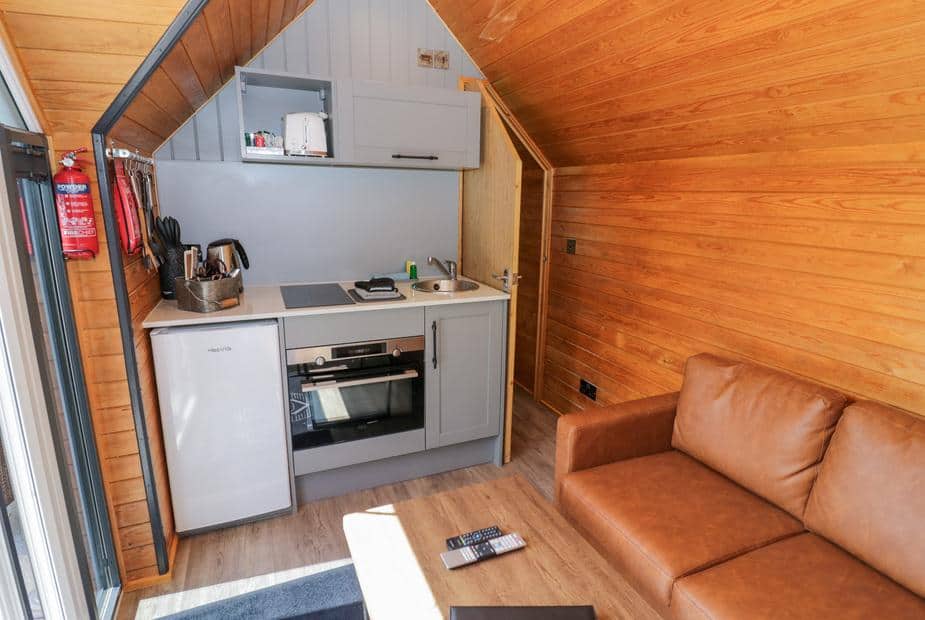 Lodge interior with compact kitchen area and brown leather sofa