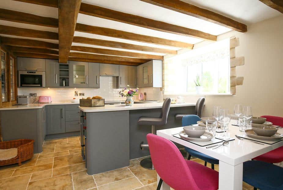 Kitchen with exposed beams, dining table and breakfast bar with chairs