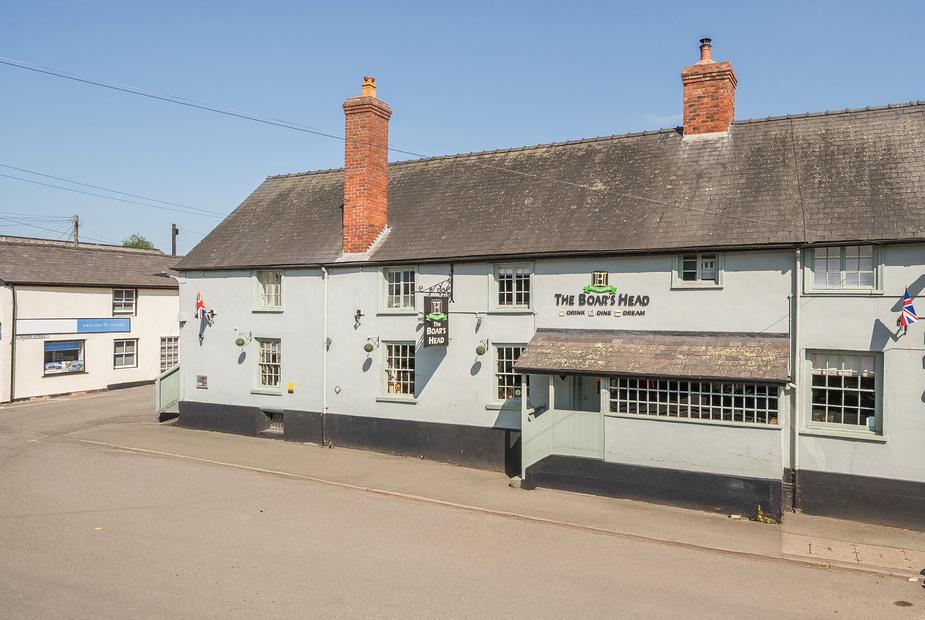 The Boars Head Pub exterior with sign and two red brick chimneys