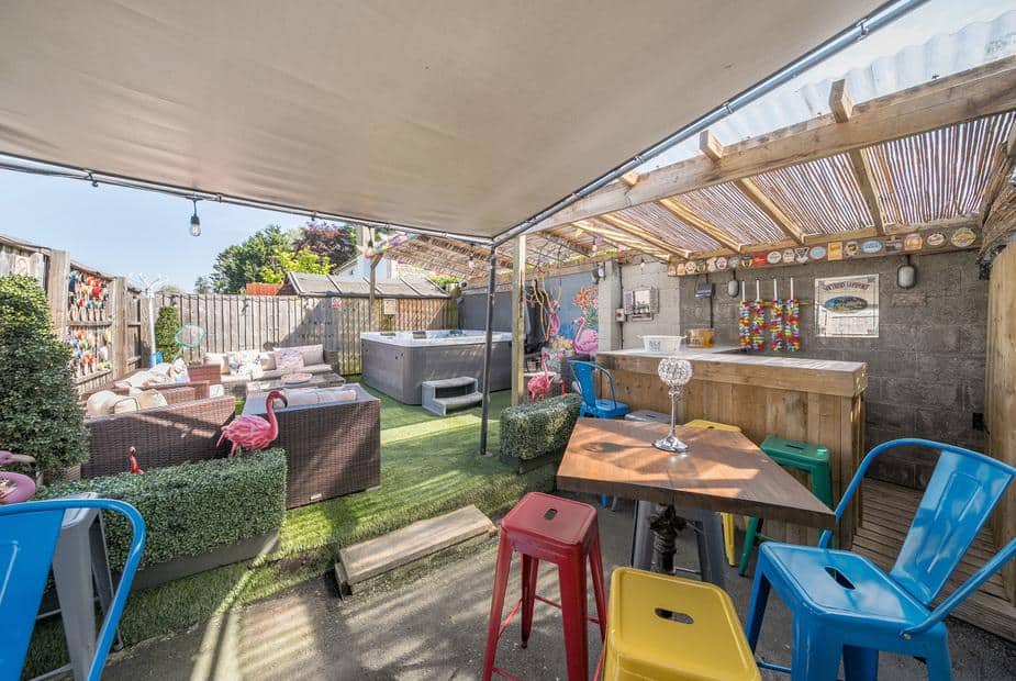 Covered patio area with bar, hot tub and seating in cottage garden