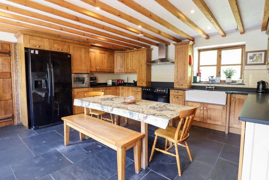 Cottage kitchen with wooden units, farmhouse sink and dining table with bench seating
