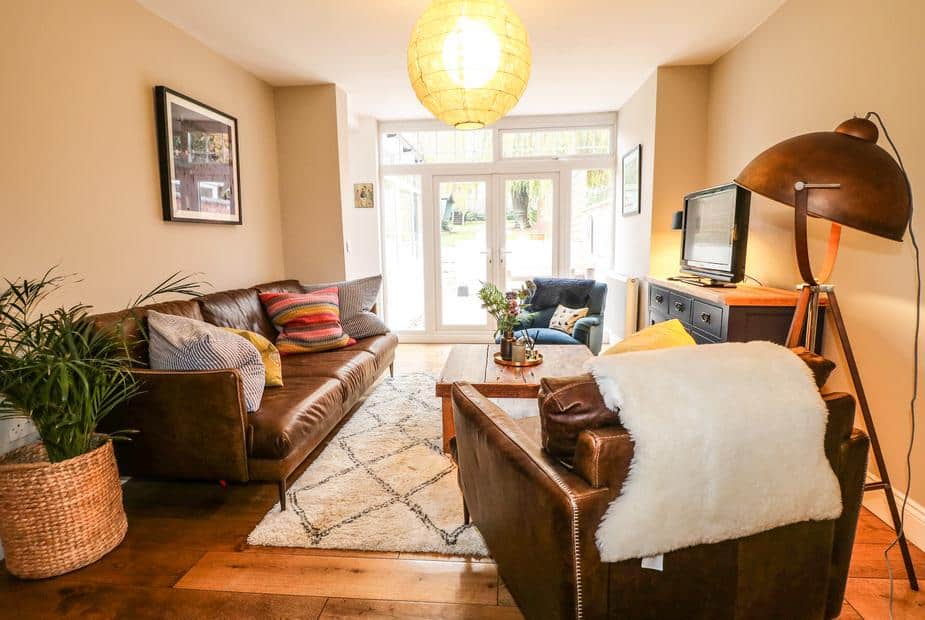 Cottage living room with leather sofas, rug, and French doors to garden