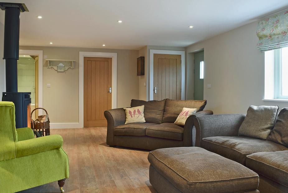 Cottage living room with wood burner, sofas and a green armchair