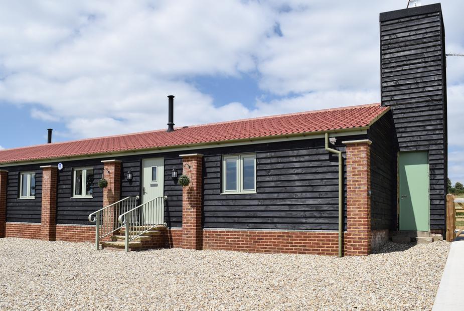 Cottage exterior with black timber cladding, red roof tiles and gravel driveway