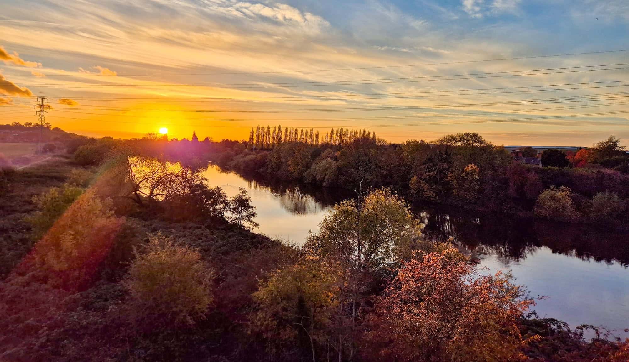 Sunset over the River Trent in Nottinghamshire, with trees reflecting on calm water.
