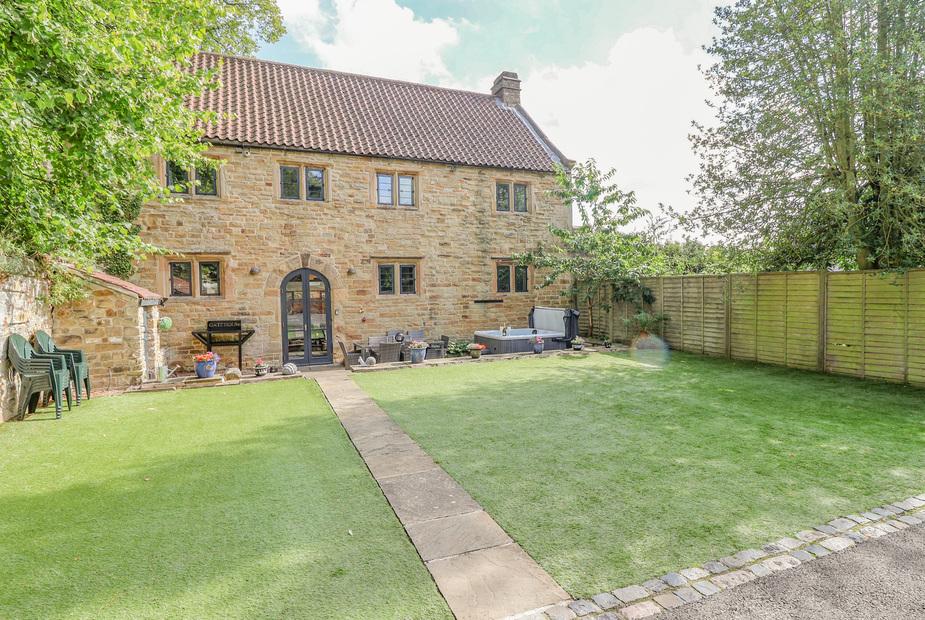 The Gatehouse stone cottage exterior with private lawn and hot tub.