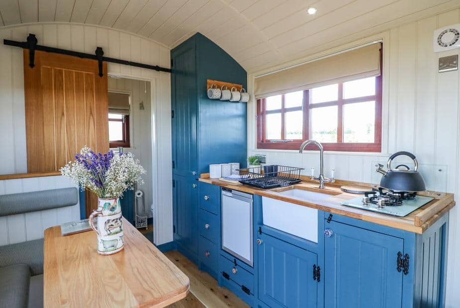 Lodge kitchen with blue cabinets, gas hob, and dining table with vase of flowers