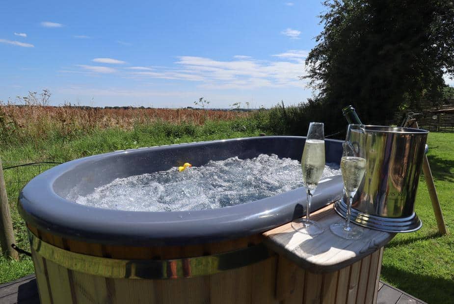 Lodge hot tub with champagne glasses and ice bucket on wooden side table