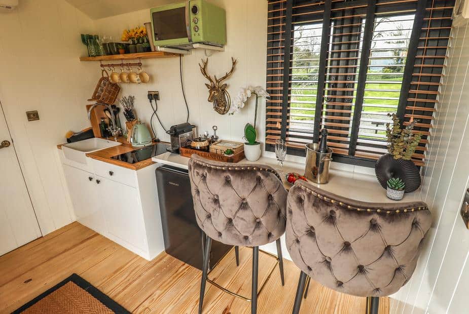 Lodge kitchen with breakfast bar and two upholstered chairs by window blinds