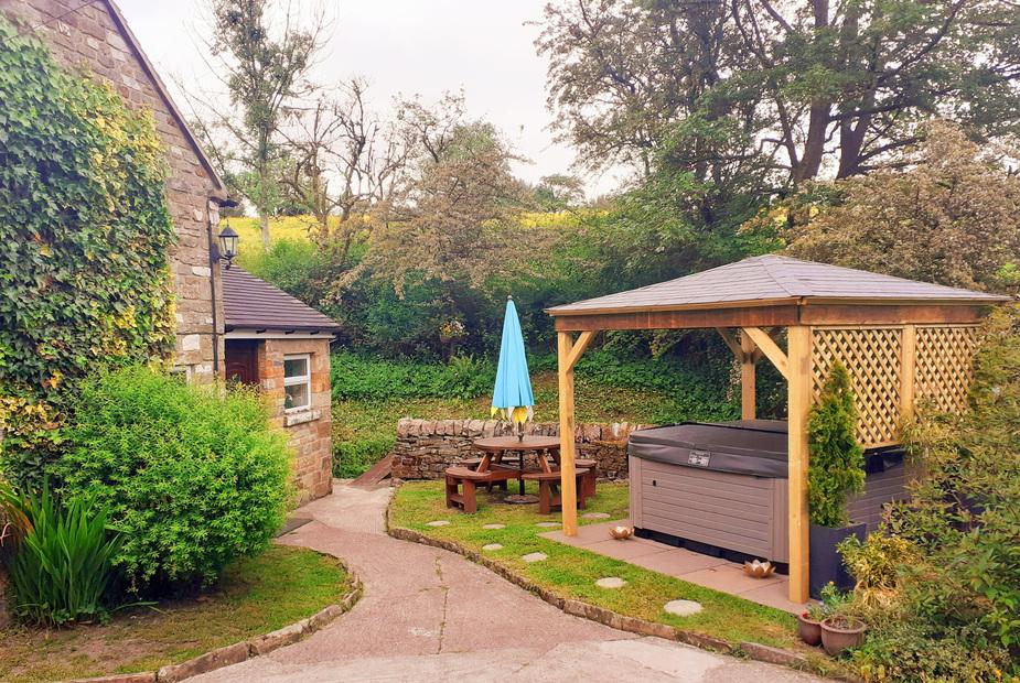 Cottage garden with wooden gazebo, hot tub and picnic table with umbrella