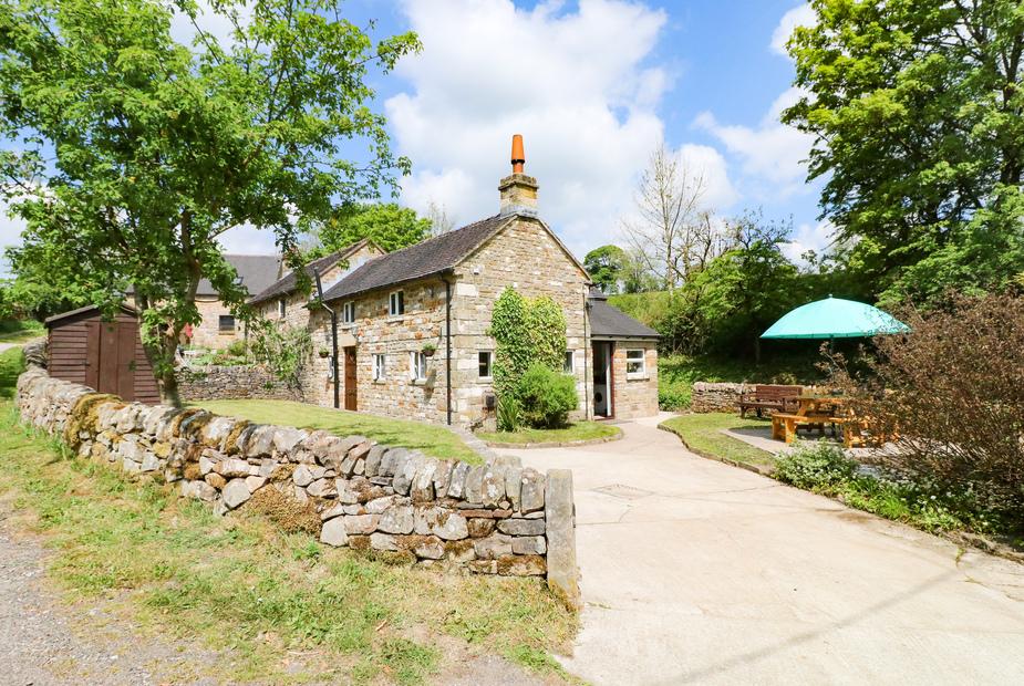 Hoobrook Cottage with stone walls and outdoor seating area under a green parasol