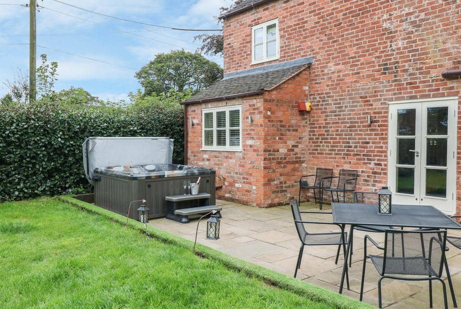 Orchard Barn brick exterior with outdoor hot tub and patio seating area