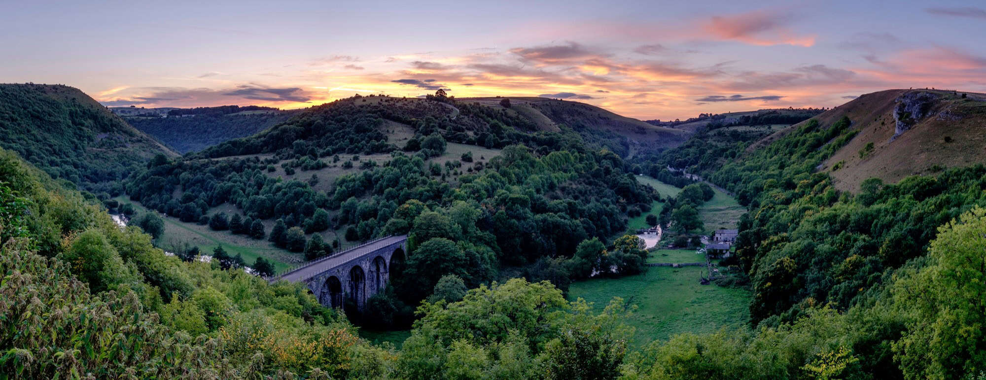 Sunset illuminating the historic Headstone Viaduct and lush green Wye Valley at Monsal Head, Derbyshire.