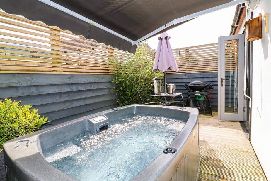Cottage patio with hot tub, outdoor table and barbecue grill
