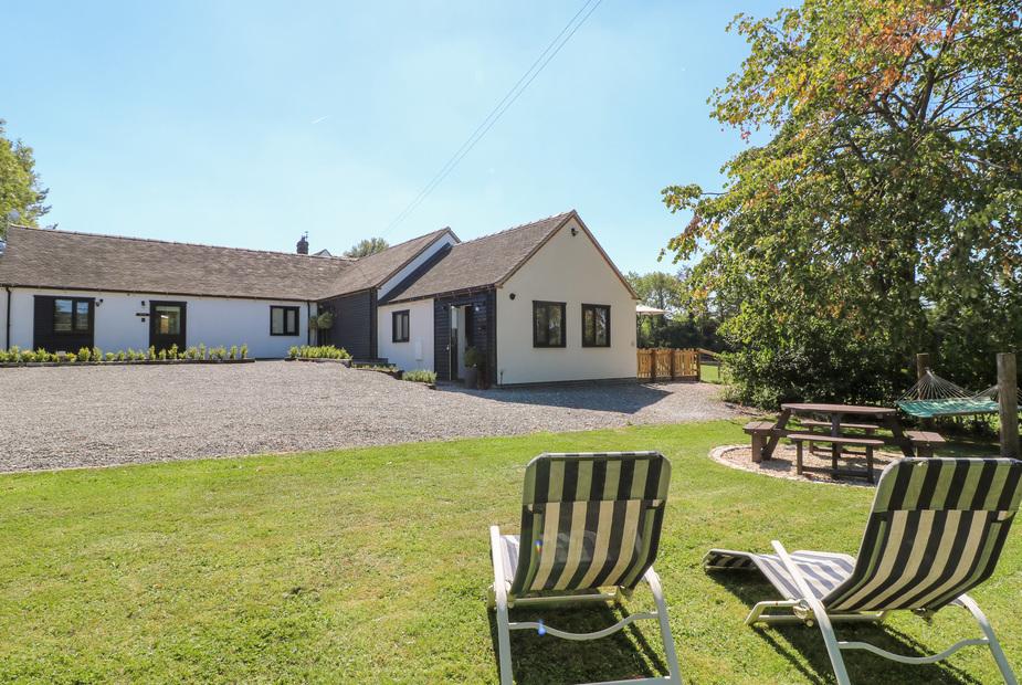 The Den exterior with lawn chairs, picnic table and hammock in the garden