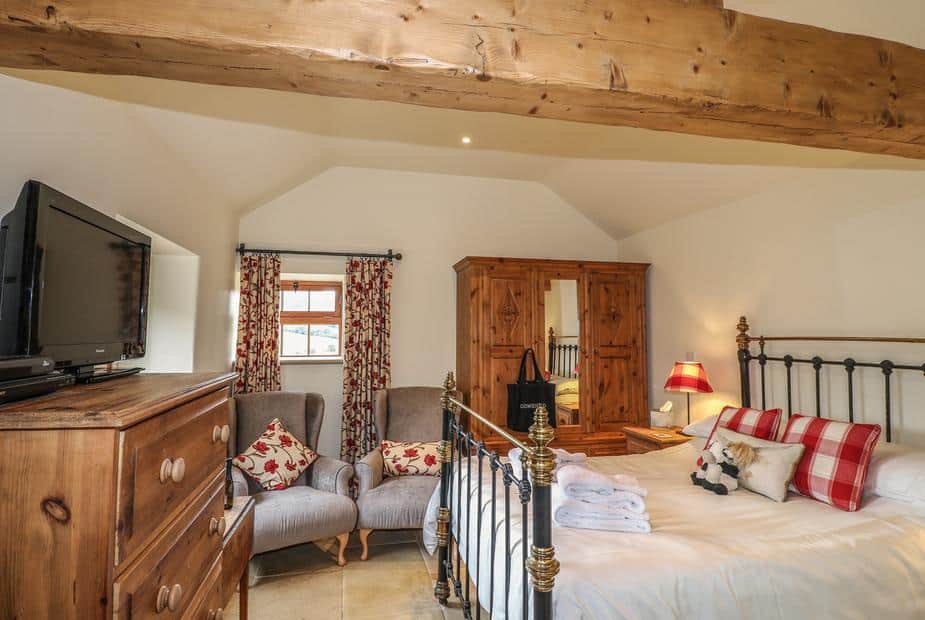 Cottage bedroom with iron bed, wooden wardrobe, and chest of drawers