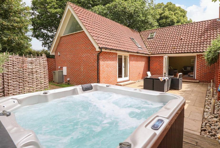 Oak Tree Lodge exterior with private hot tub on stone patio and open outdoor seating area