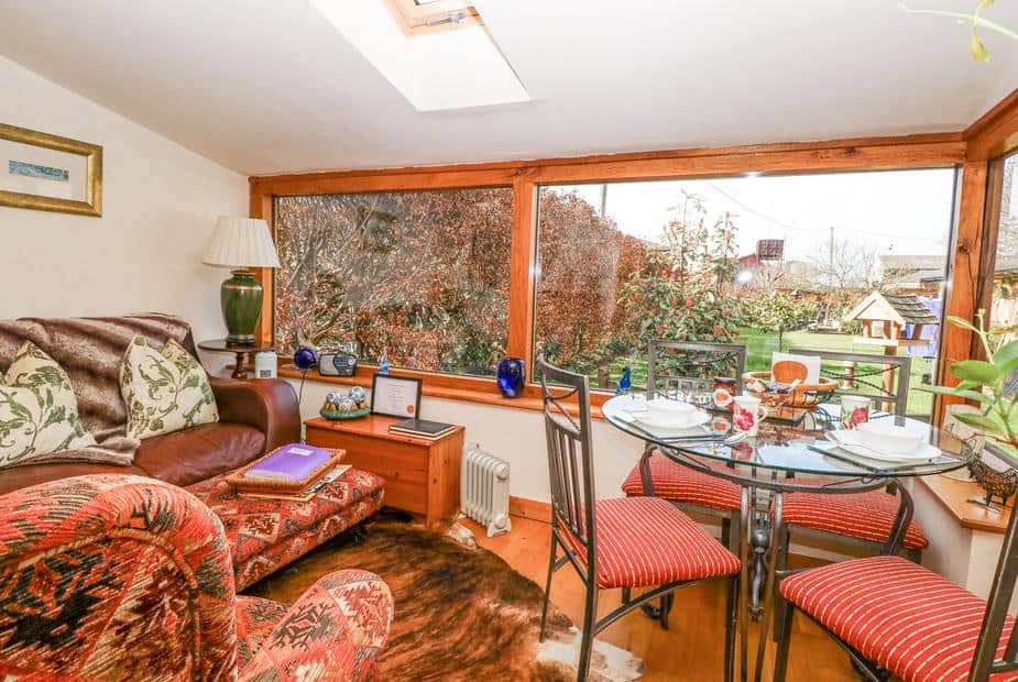 Lodge living area with glass dining table and large windows overlooking garden