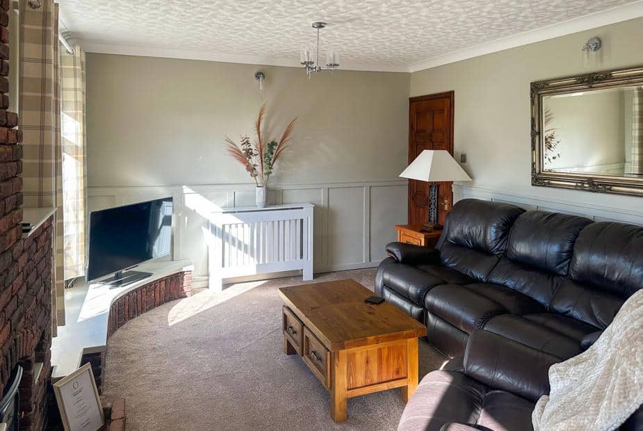 Lodge living room with black leather sofa, wooden coffee table and TV in corner